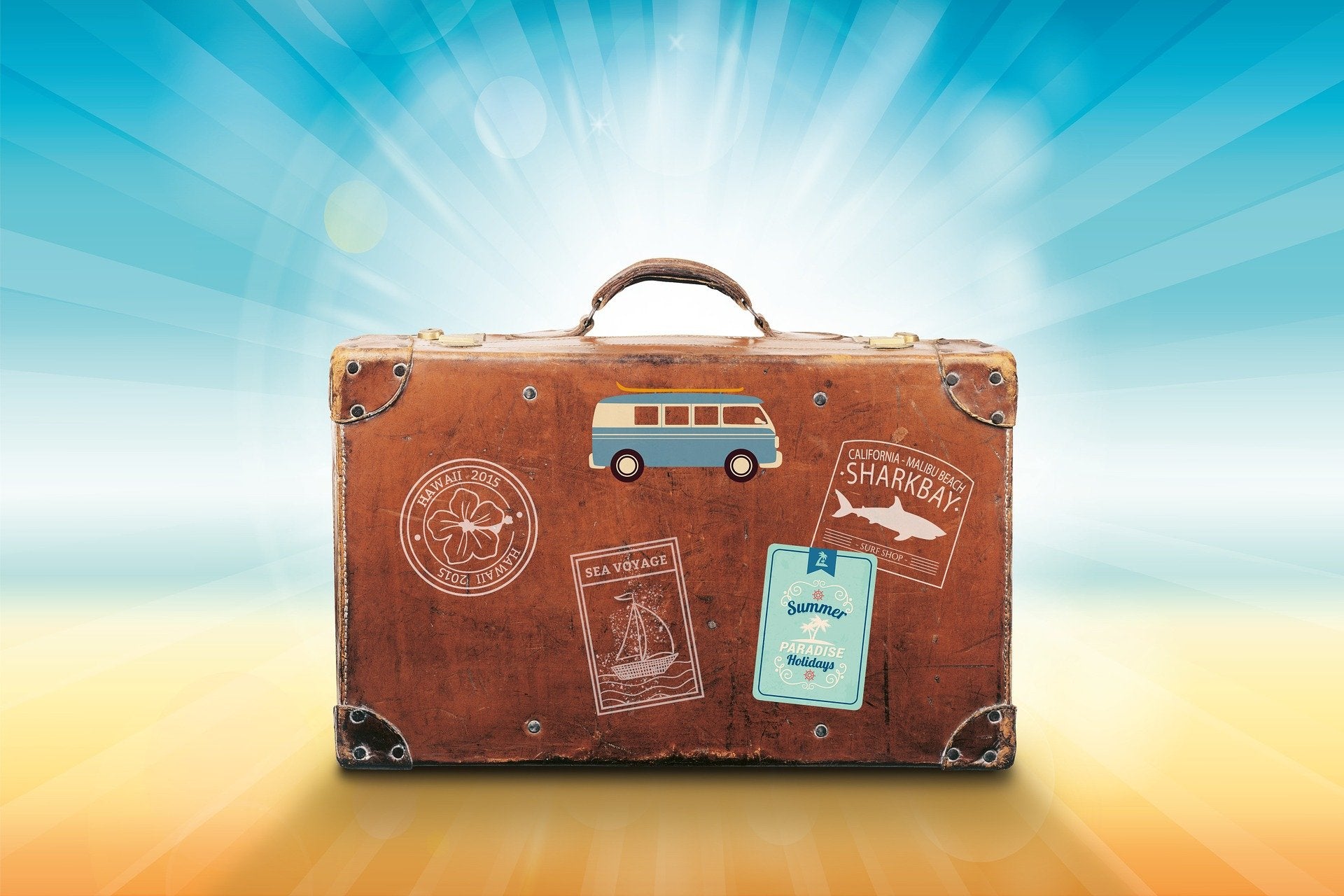 Suitcase with travel stickers on a sunny beach